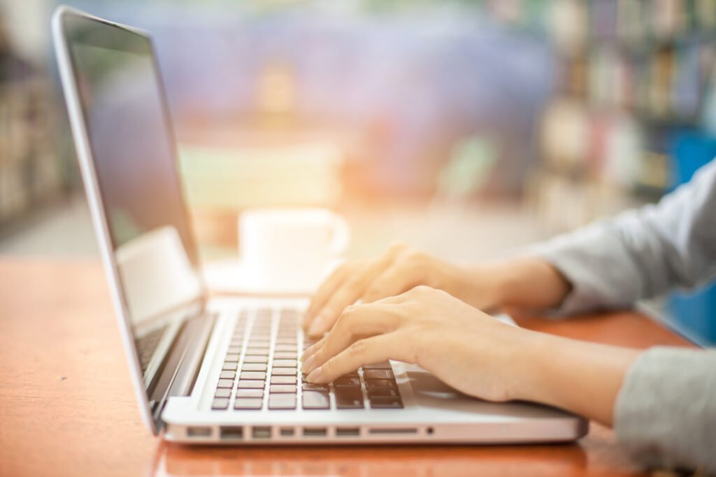woman's hands using laptop with blank screen on table in offie