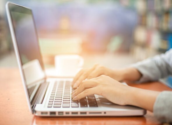 woman's hands using laptop with blank screen on table in offie